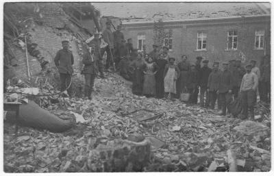 Mensen poseren bij gebouw in puin na bombardement, wellicht deel van klooster