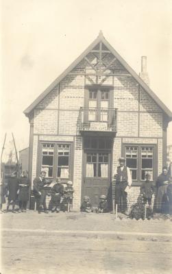 Familiefoto bij huis met opschrift: 'De Wahtzaal, Bier, Kafé', Dadizele