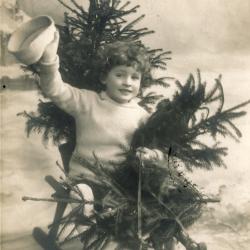 Beeldzijde kerstkaart, kindje op slede met sparren, 1910