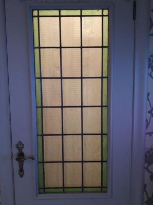 Rechthoekig glasraam met groene kader in deur