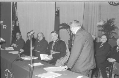 Lachende Mgr. Desmedt houdt een boek in de hand, Izegem 1957