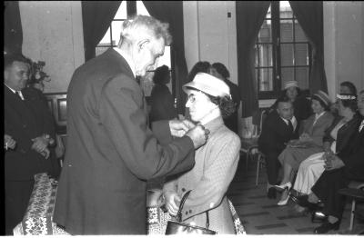 Huldiging gedecoreerden Unions: burgemeester speldt het ereteken op bij een mevrouw, Izegem 1957